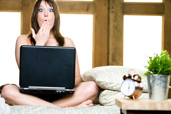 Woman surprised while using laptop in bedroom